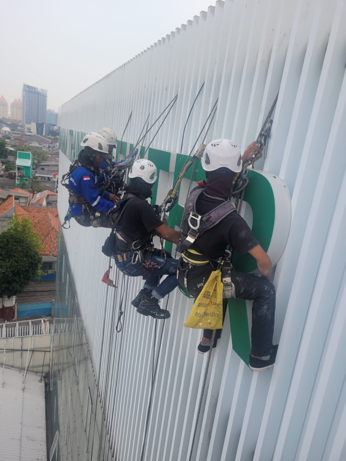 Tim rope access melakukan pekerjaan pada façade